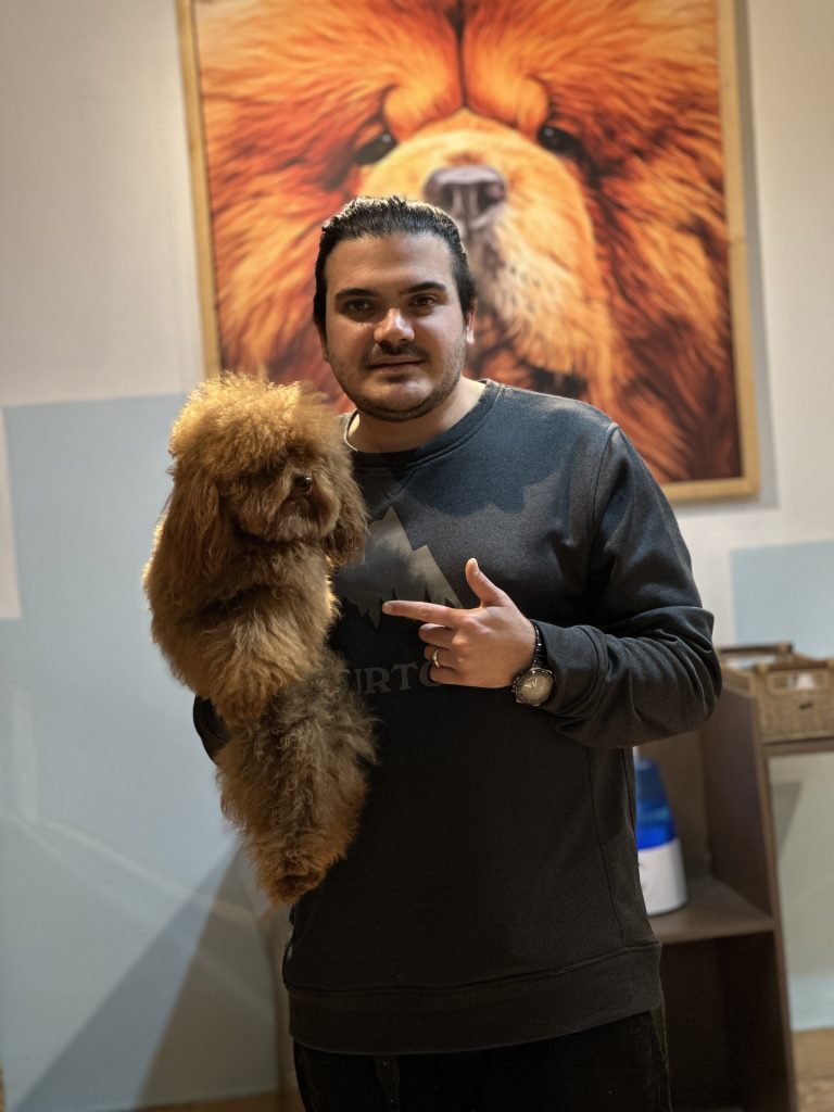 "A man holding a large fluffy poodle in his hands at home."