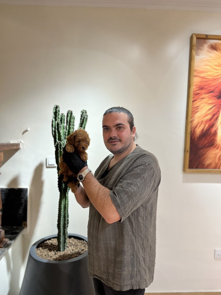 "A man holding a brown toy poodle in his hands."